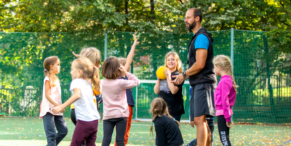 Montessori guide with kids during physical education class on playground